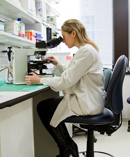 Scientist in a lab looking through a microscope